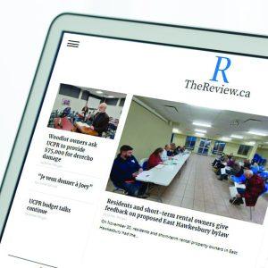 A tablet displaying thereview.ca on the screen to promote Review website display advertisement