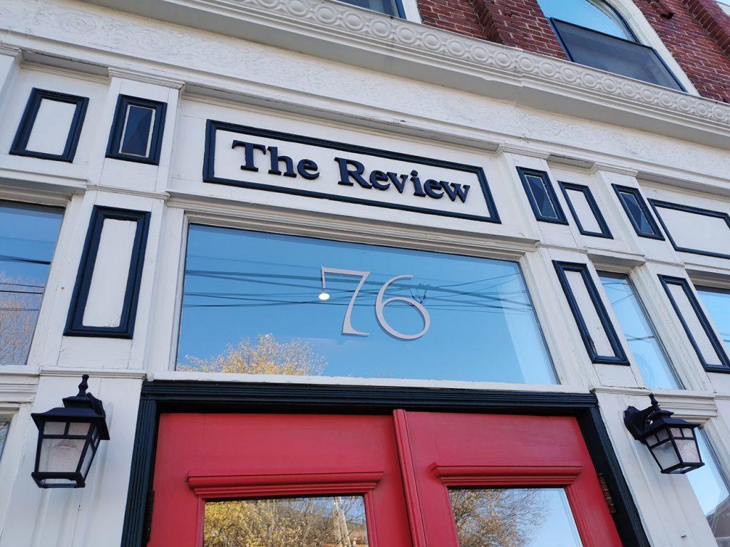 Outside the Review Offices looking up at the sign. You see the top of red doors and a big number 76 showing.