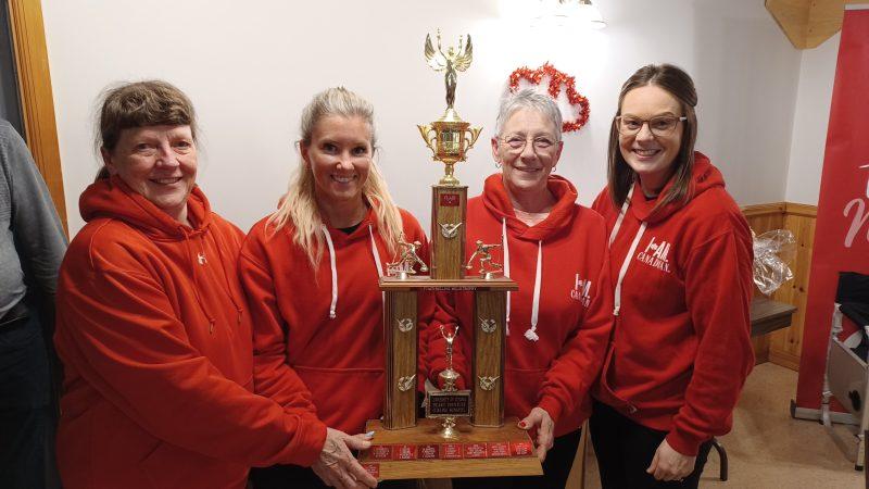 This is a photo taken by James Morgan of the winning team at the Bonspiel holding their trophy, from left to right, Lead Sandra Robinson, Skip Kyla Burwash, Second Sandra Cummings, and Third/Vice Ashton MacDonald.